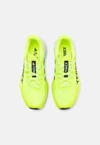 Neon geltonos sportinės bateliai su tinklelio viršumi, juodomis detalėmis ir baltu padu. Yra raišteliai ir "TERREX" prekės ženklas šonuose.