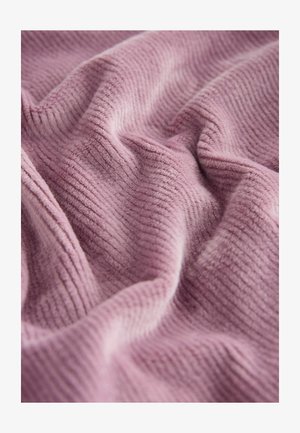 Miękka, żebrowana tkanina w stonowanym różowym kolorze, z teksturowanymi, falistymi zwojami. Powierzchnia wygląda na puszystą i zachęcającą.