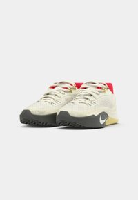 Sneakers med en overdel i cremefarvet mesh, røde accenter, grå gummisål og et hvidt logo. Funktionen rund form og teksturerede syninger.