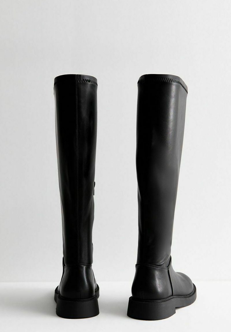 Schwarze Lederstiefel bis zum Knie mit glatter Textur, flachen Sohlen und Nahtdetails. Sie verfügen über einen seitlichen Verschluss und ein minimalistisches Design.