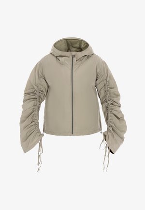 Let, beige hættejakke med rynkede ærmer og lynlås foran. Har snoretræk ved ærmekanter og kant, lavet af glat stof.