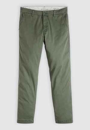 Męskie chinosy slim fit w oliwkowej zieleni, z szlufkami na pasek, zapięciem na guziki i bocznymi kieszeniami z rozcięciami, rozłożone płasko na jasnym tle.