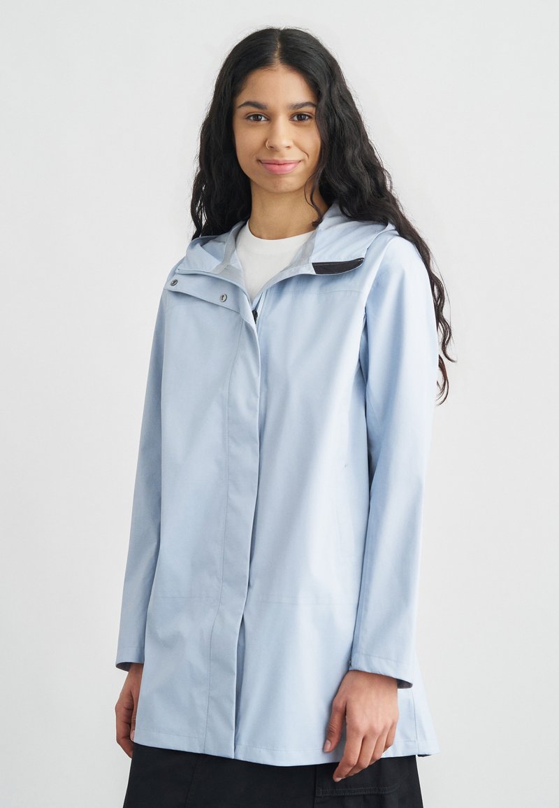 Svetlomodrá nepremokavá bunda s kapucňou, vybavená predným zipsom, cvokmi a mierne rozšíreným lemom. Hladká textúra.