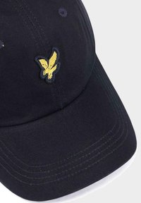 Cappello blu navy in cotone con visiera curva. Presenta un logo di una farfalla gialla ricamata sul davanti. Le cuciture sono visibili lungo la visiera.