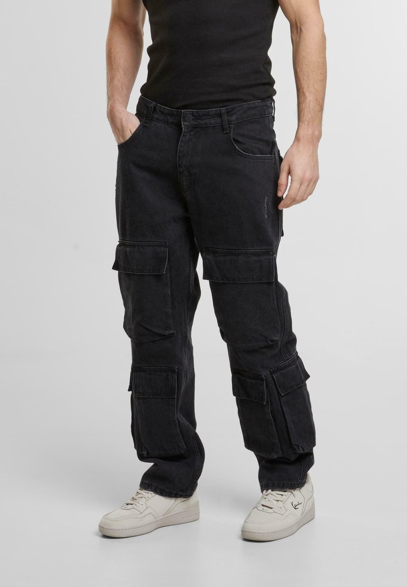 Pantaloni cargo negri din denim, cu multiple buzunare laterale, croială relaxată și o textură ușor uzată.