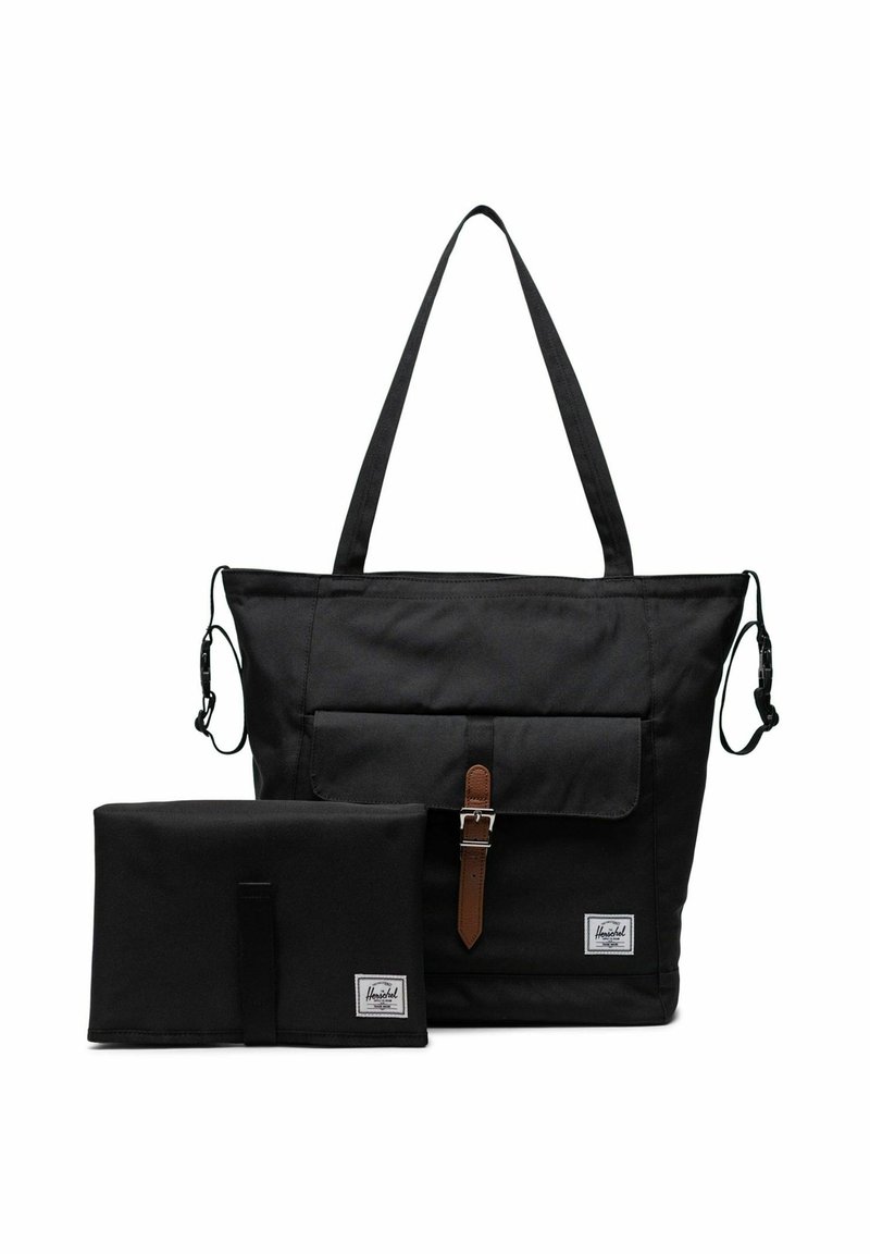 Sac fourre-tout Herschel noir avec poche avant et boucle marron, accompagné d'un matelas à langer pliable noir assorti, les deux exhibant les étiquettes de la marque.
