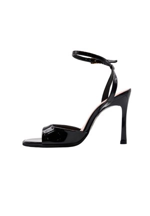 Sandalo con tacco alto in pelle verniciata nera con sottile cinturino alla caviglia e punta aperta, mostrato di profilo su sfondo bianco.