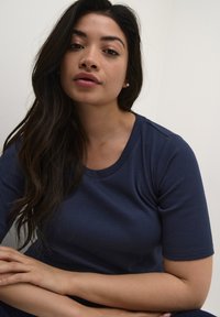Camiseta de punto en azul marino con cuello redondo y mangas cortas. La tela parece suave con un diseño ajustado. Costuras de hombro visibles.
