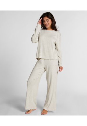 Helles beiges Loungewear-Set aus weichem Stoff, bestehend aus einem locker sitzenden Langarmoberteil und weit geschnittenen Hosen mit ausgefransten Säumen.