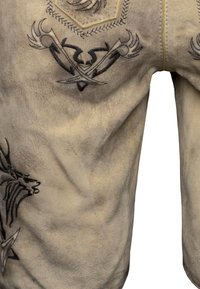 Beige suède broek met zwarte geborduurde ontwerpen van gekruiste zwaarden en een hertenkop.