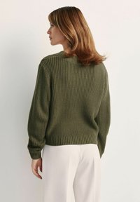 Zielono-oliwkowy sweter z dzianiny o prążkowanej strukturze, okrągłym dekolcie i długich rękawach. Krótki krój z jednolitym paskiem w talii.