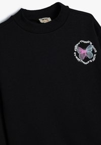 Zwarte katoenen sweatshirt met een geribde hals en een kleurrijke vlinderafbeelding met de tekst "EVERYTHING'S NICE". Zachte textuur, casual ontwerp.