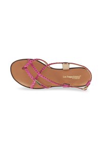 Sandal in finta pelle intrecciata rosa con suola piatta, dotato di cinturini incrociati e una fibbia in tono oro. Progettato per essere indossato con le dita dei piedi scoperte.