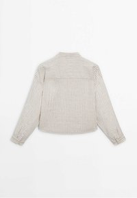 Chemise à manches longues rayée beige et blanche avec des rayures horizontales sur le haut du dos et des rayures verticales sur le bas du dos et les manches.