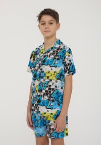 T-shirt a maniche corte con grafica, nei colori nero, bianco e blu vivace con accenti gialli, caratterizzato da un motivo in stile graffiti e una vestibilità ampia.