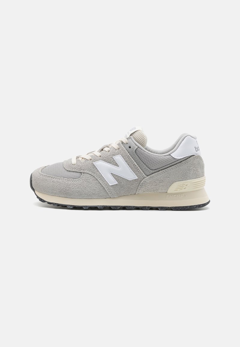 Baskets New Balance gris et blanches avec dessus en daim et mesh, semelle intermédiaire beige, semelle extérieure noire et logo "N" blanc sur le côté.