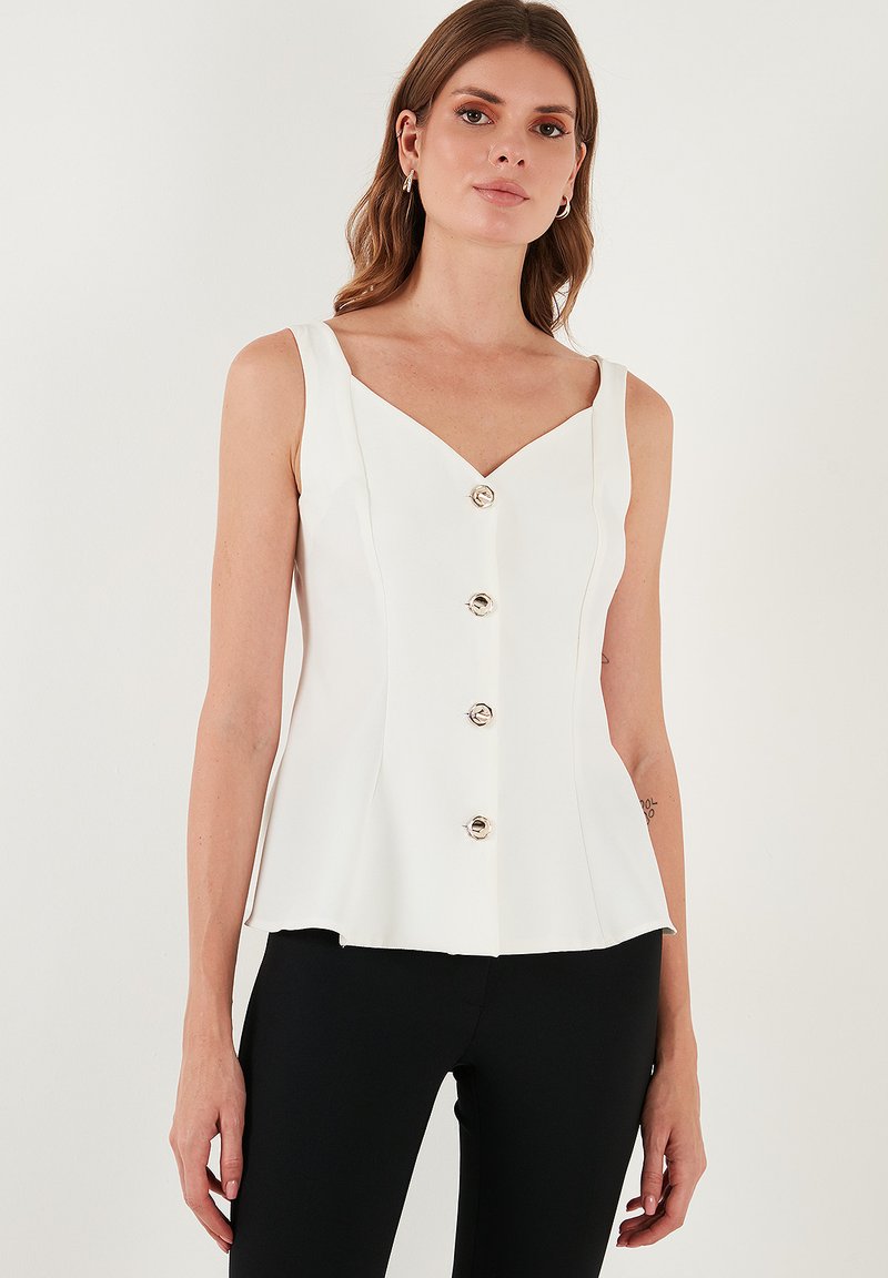 Fehér ujjatlan felső V-nyakkivágással, az elején öt ezüstgombbal és bővülő aljjal. Sima anyag, amely egy letisztult sziluettet alkot.