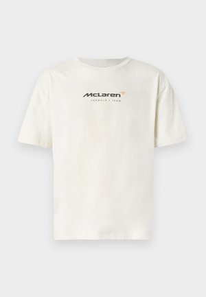 T-shirt en coton blanc avec un col rond et des manches courtes. L'avant présente "Équipe McLaren de Formule 1" en texte noir et orange.