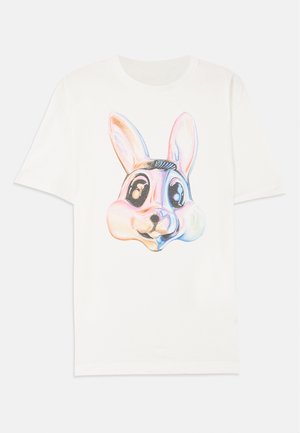 T-shirt blanc avec un grand graphique d'un visage de lapin de style cartoon, coloré, avec des yeux distincts et des oreilles proéminentes, fabriqué en coton doux.