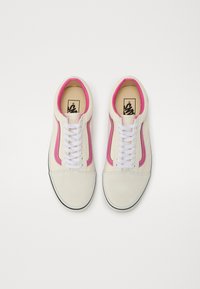 Hvide kanvas sneakers med lyserøde side-striber, hvide snørebånd, rund tå, kontrasterende sort sål og en tekstureret overdel.