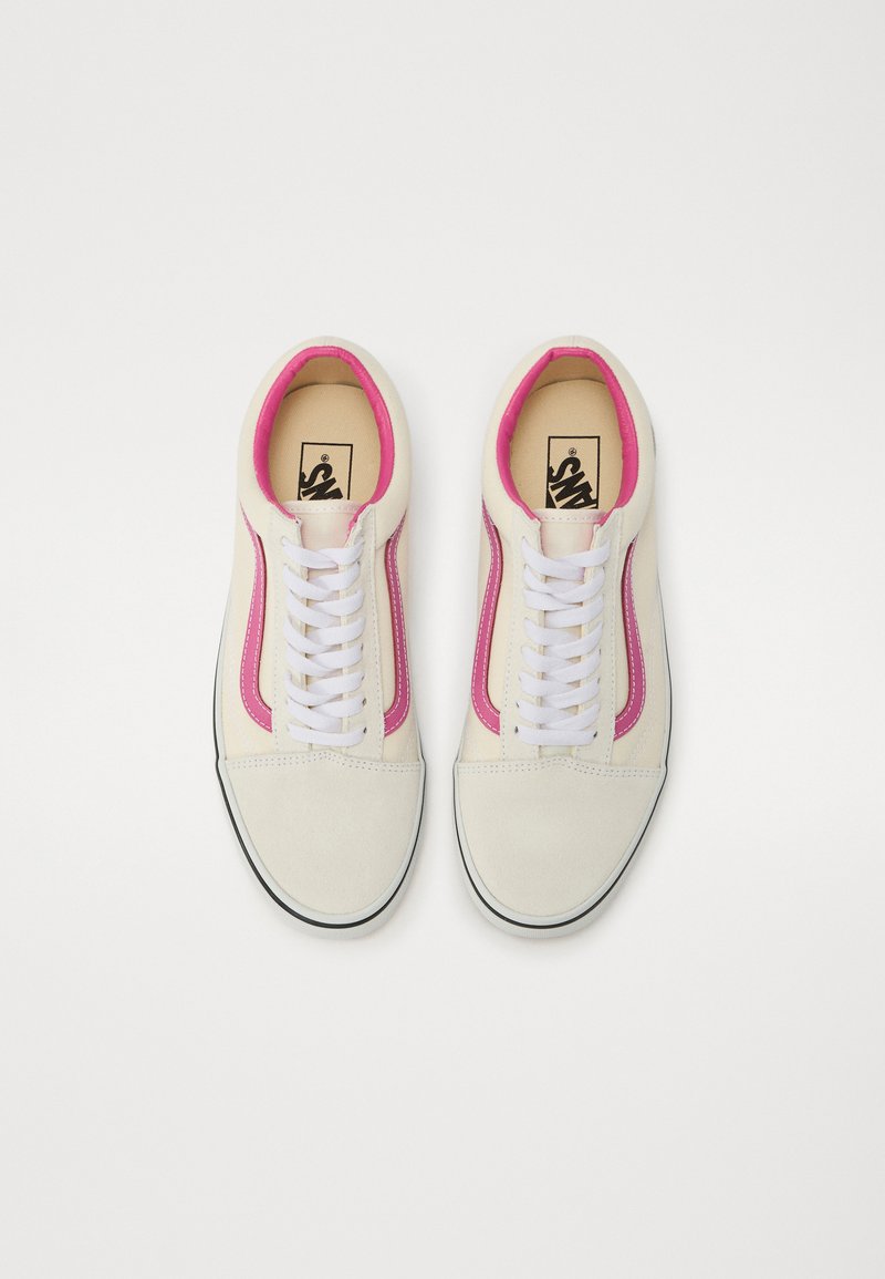 Zapatillas blancas de lona con rayas laterales rosas, cordones blancos, puntera redonda, suela negra en contraste y parte superior texturizada.