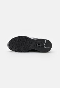 Semelle de sneaker noire avec motif de bande de roulement texturé, coussin d'air ovale central et petit logo Swoosh près du talon.
