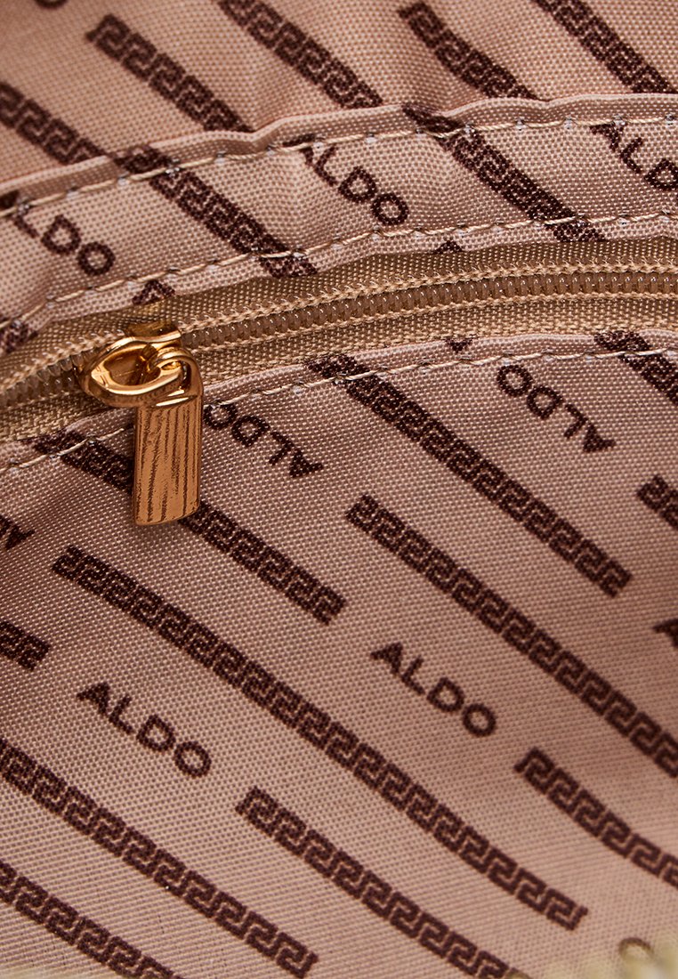 Tissu beige avec un motif "ALDO" marron répété, présentent un zip doré et une texture lisse, mettant en valeur un design minimaliste.