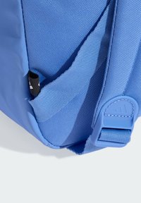 Mochila azul con tejido texturizado y acentos suaves. Incluye correas ajustables y un pequeño detalle del logo en negro.