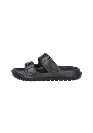 Sandalia negra sin cierre con dos tiras ajustables con hebilla y suela texturizada, diseñada para uso casual y comodidad.