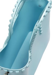 Borsa tote blu realizzata in plastica morbida, con bordi borchiati, superficie liscia e due manici per il trasporto. L'interno è ampio e non decorato.