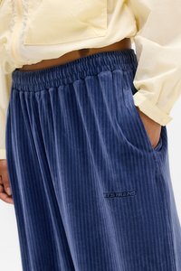 Navyblauwe ribfluwelen broek met verticale strepen, elastische tailleband en zijzakken. Voorzien van een klein logoplaatje aan de voorkant.