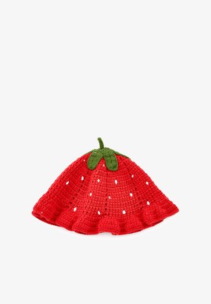 Czerwona szydełkowana czapka w kształcie truskawki z małymi otworami oraz zielonymi listkami i gałązką na górze, ułożona płasko na białym tle.