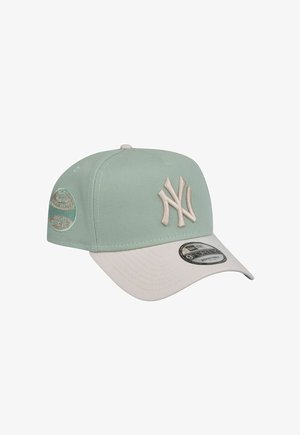 Cappellino da baseball verde menta con visiera bianca, presenta un logo ricamato, cinturino regolabile e texture intrecciata. Dettaglio della toppa laterale di rilievo.