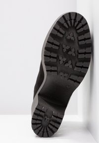 Musta kumipohja, jossa on syvä kuvio, hieman kaarevat reunat. Sileä pinta, jossa on kohokuvioitu brändäys. Suunniteltu vetovoimaksi ja kestävyydelle.