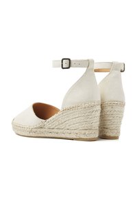 White suede wedge sandals with a woven jute heel and ankle strap, featuring a rounded toe and minimalistic design.