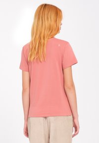 Korte mouw, koraalroze T-shirt met een ronde hals, gemaakt van zachte katoen. Bevat een klein logodetail op de bovenrug.