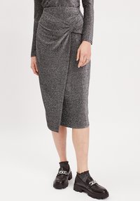 Gonna a matita grigia e scintillante con dettaglio drappeggiato sul davanti, abbinata a scarpe nere chunky e calze texturizzate. Tessuto liscio con una vestibilità aderente.
