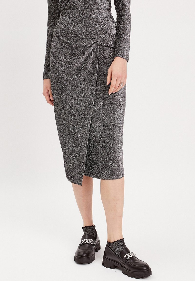 Gonna a matita grigia e scintillante con dettaglio drappeggiato sul davanti, abbinata a scarpe nere chunky e calze texturizzate. Tessuto liscio con una vestibilità aderente.