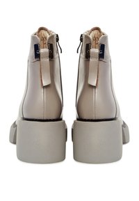 Beige leren enkellaarsjes met een gladde afwerking, stevige grijze hakken en ritssluitingen aan de achterkant. Inclusief een klein lusje aan de achterkant.