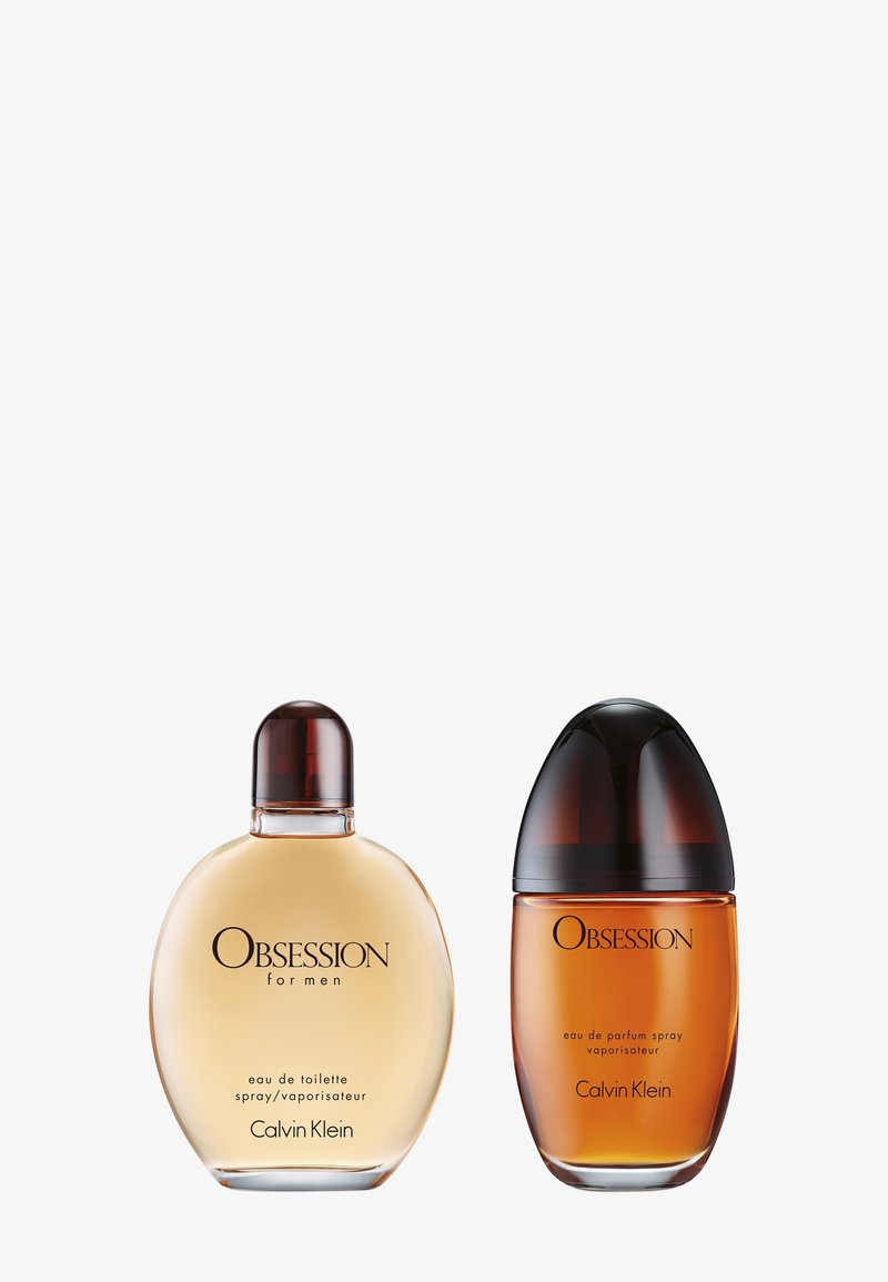 Deux flacons de parfum : à gauche, un flacon rond en verre transparent contenant un liquide doré, avec un capuchon marron ; à droite, un flacon ovale en verre ambré avec un capuchon sombre, contenant un liquide plus riche.