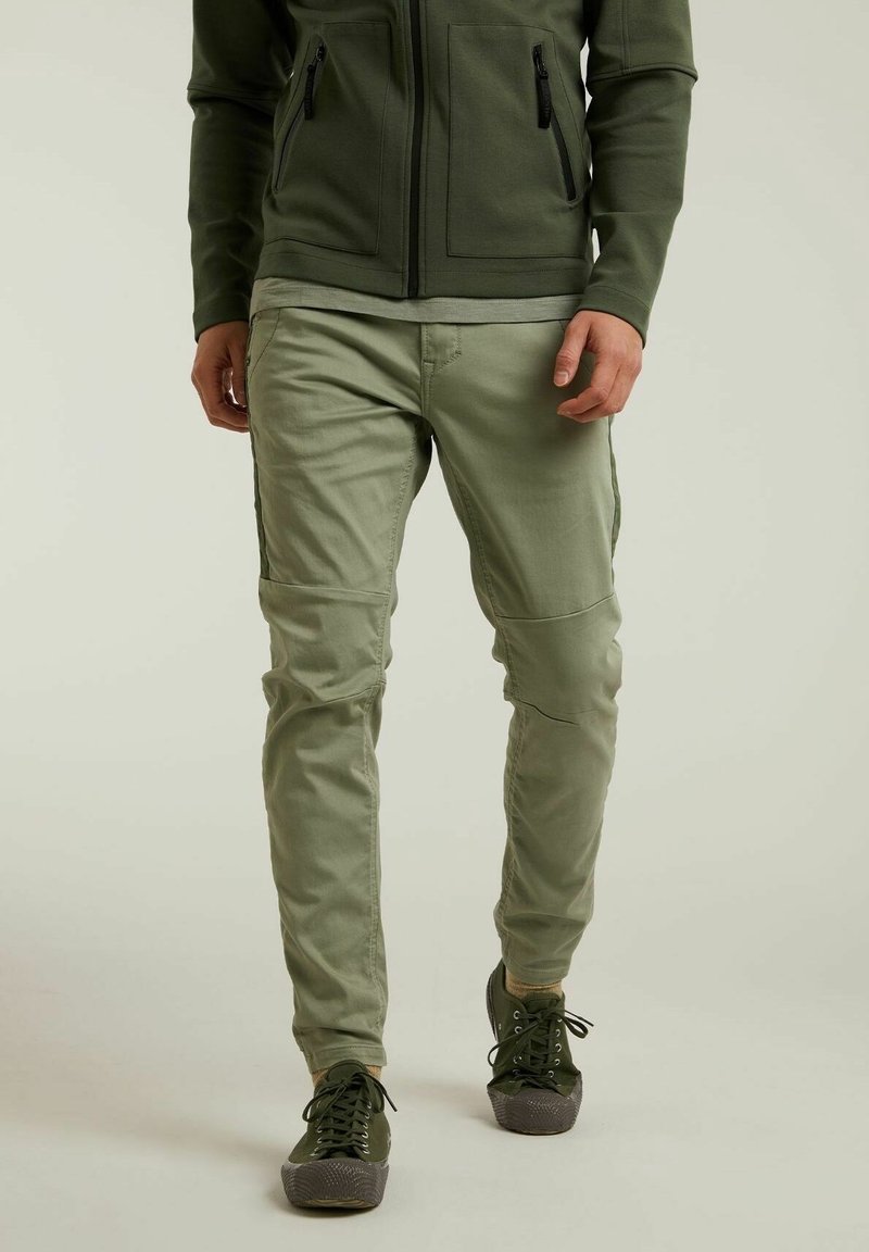 Ljusgröna cargobyxor med flera fickor och en tapered passform, kombinerade med mörkgröna skor, visar en avslappnad design och en mjuk textur.