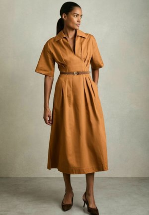 Abito midi in cotone marrone con maniche corte, vita con cintura e tasche laterali. Il tessuto presenta una superficie liscia e un design strutturato.