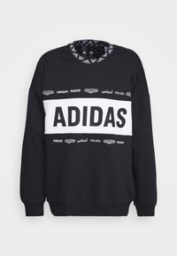 Czarna bluza z białym logo "ADIDAS" na klatce piersiowej, z wzorzystym kołnierzykiem i tekstem w różnych językach. Materiał z mieszanki bawełny.