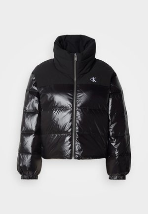 Must musternahk, millel on läikiv viimistlus, kõrge kaelus ja massiivne lukk. Omab soonikuid mansette ja logo vasakus ülanurgas.