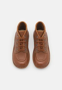 Bottines en cuir marron avec un bout rond, une tige texturée, des œillets en métal et des détails cousus. Elles sont dotées de lacets marron et d'un col rembourré.