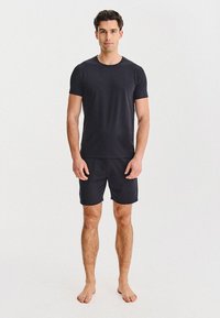 Czarny t-shirt z krótkim rękawem i pasującymi szortami wykonany z miękkiego materiału, z prostym wzornictwem i dopasowanym krojem, bez widocznych logotypów.