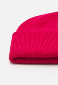 Gorro de lana de punto de color rosa con borde doblado, que presenta una fina textura de canalé y un diseño sin costuras. Material suave y flexible.