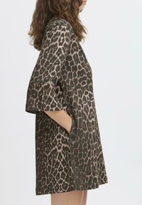 Kurzes Kleid mit Leopardenmuster in Dunkelgrün und Braun, mit lockerer Passform, kurzen Ärmeln und seitlichen Taschen. Glatte Stofftextur.