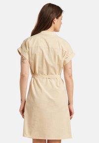 Kleid in hellbeige aus leichten Stoff mit umgeschlagenen kurzen Ärmeln, einem Kragen und einem Taillengürtel. Verfügt über einen glatten, strukturierten Stoff mit einer entspannten Passform.