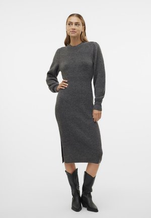 Graues Strick-Midi-Kleid mit langen Ärmeln und seitlichem Schlitz. Weicher Stoff, runder Ausschnitt, figurbetonte Silhouette. Modell trägt schwarze Cowgirl-Stiefel.